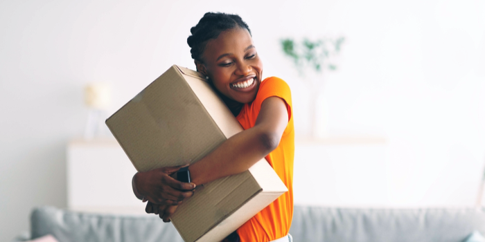Eine Frau umarmt ein Paket und lächelt.