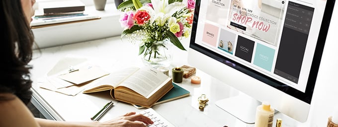 Junge Frau macht Smart Working am Schreibtisch mit aufgeklapptem Buch und Computer.