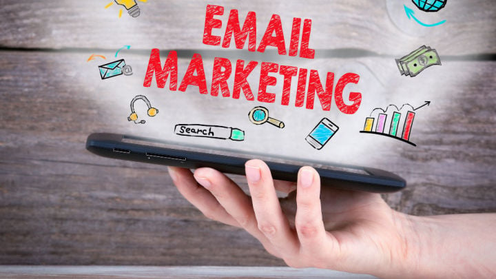 Eine Person hält ein Tablet in der Hand. Darüber steht in roter Schrift: E-Mail-Marketing.