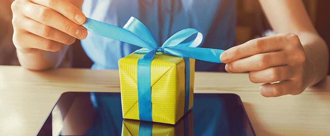 Eine Person öffnet ein verpacktes Geschenk.
