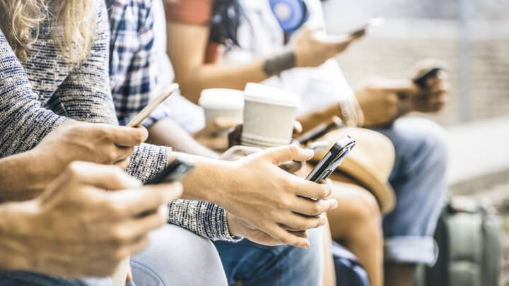 Mehrere Personen sitzen nebeneinander und halten ihr Smartphone in der Hand.