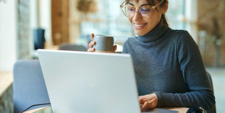 Eine Frau mit Brille sitzt vor einem Laptop.