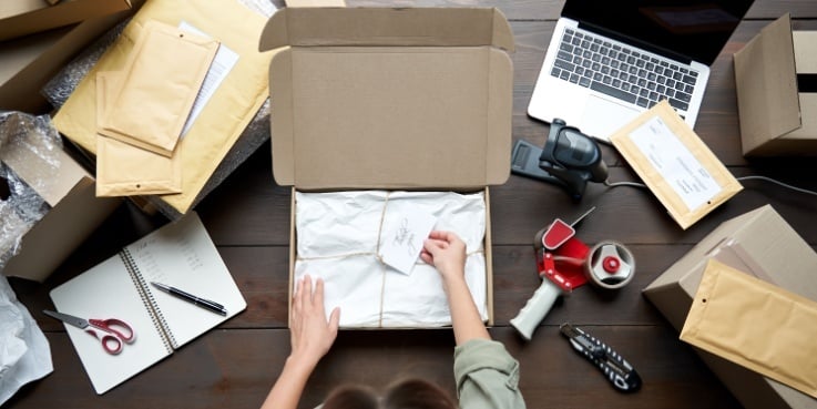Eine Frau verpackt Ware in einem Paket.