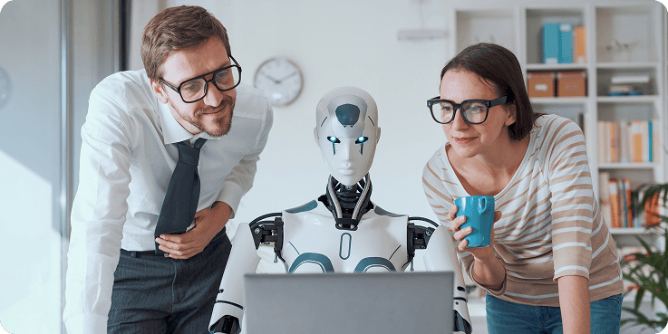 Zwei Menschen und ein Roboter schauen in ein Laptop.