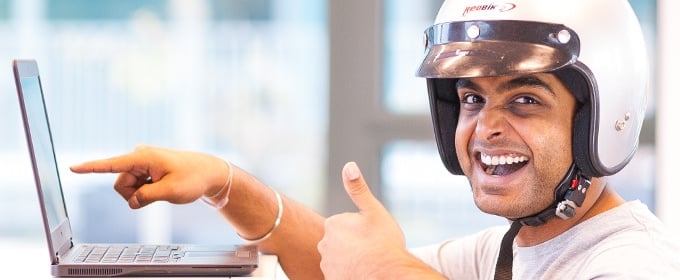 Geschützter Mann mit Helm zeigt begeistert auf seinen Laptopbildschirm